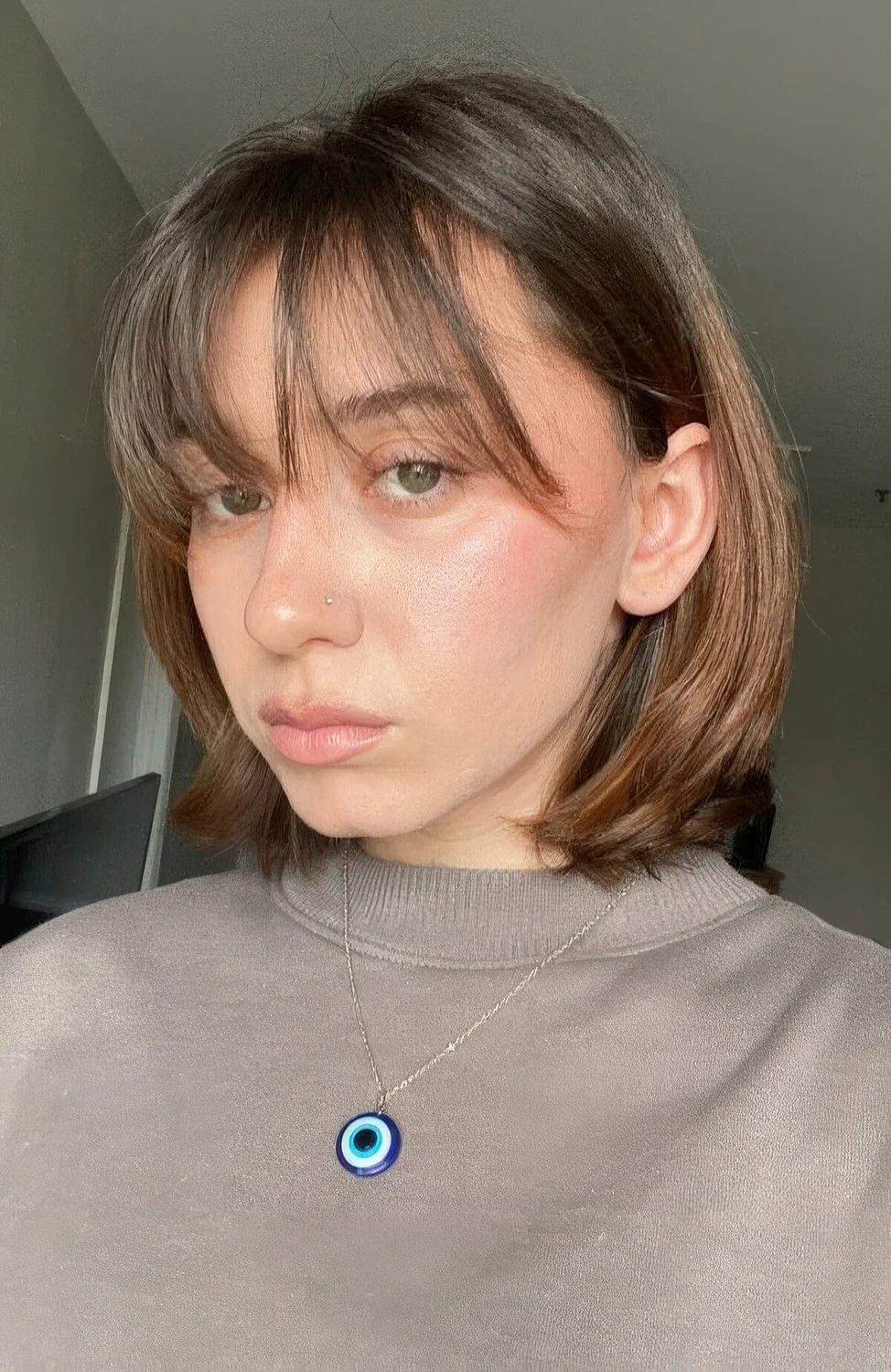 Brown medium bob with highlights and wispy bangs.