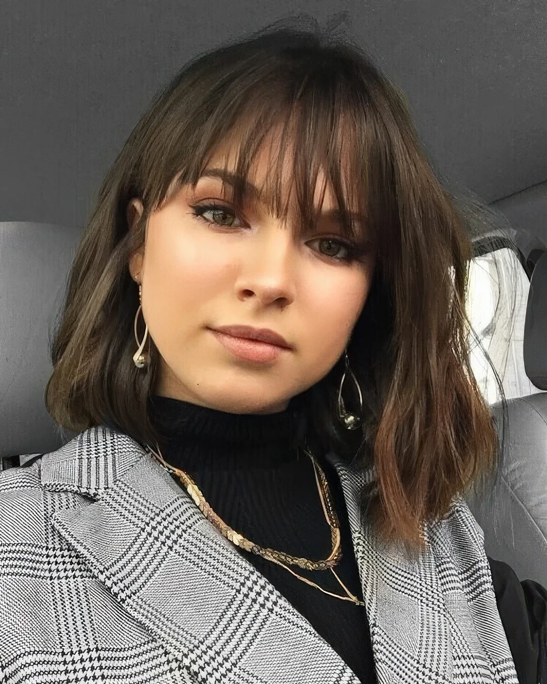 Brown outgrown wavy bob with wispy outgrown bangs.