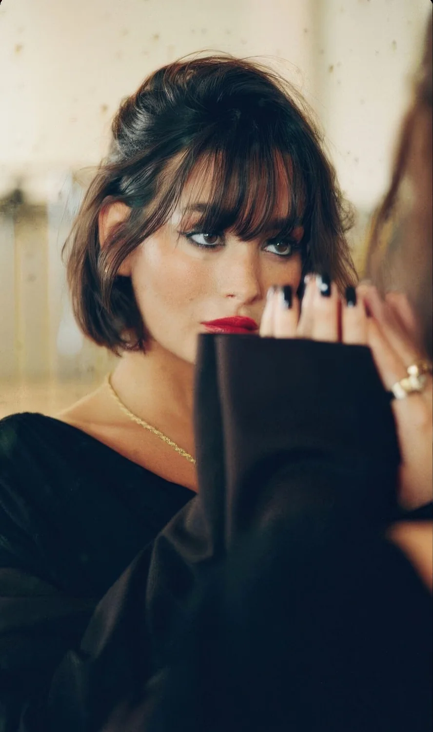 Dark brown chin-length bob with wispy outgrown bangs.