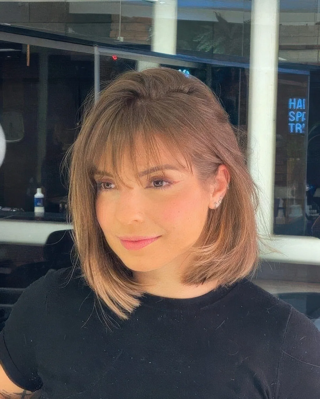 Long brown bob with ombre and blonde highlights and wispy bangs.
