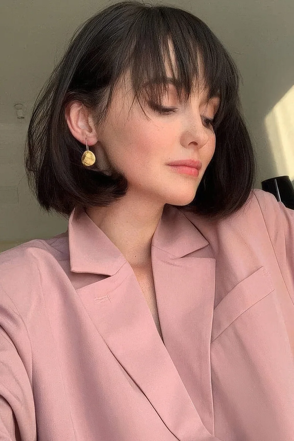 Medium black bob with rounded ends and wispy bangs that accent the eyes and the face.