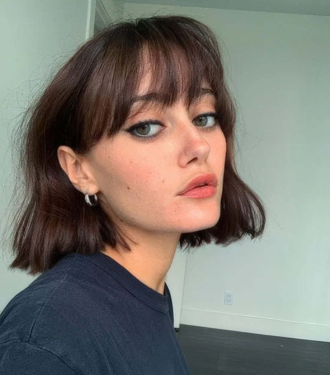 Messy wavy dark brown chin-length bob with wispy bangs.