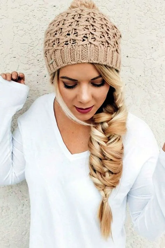 Large twisted fishtail braid and a neutral beanie look glam together.