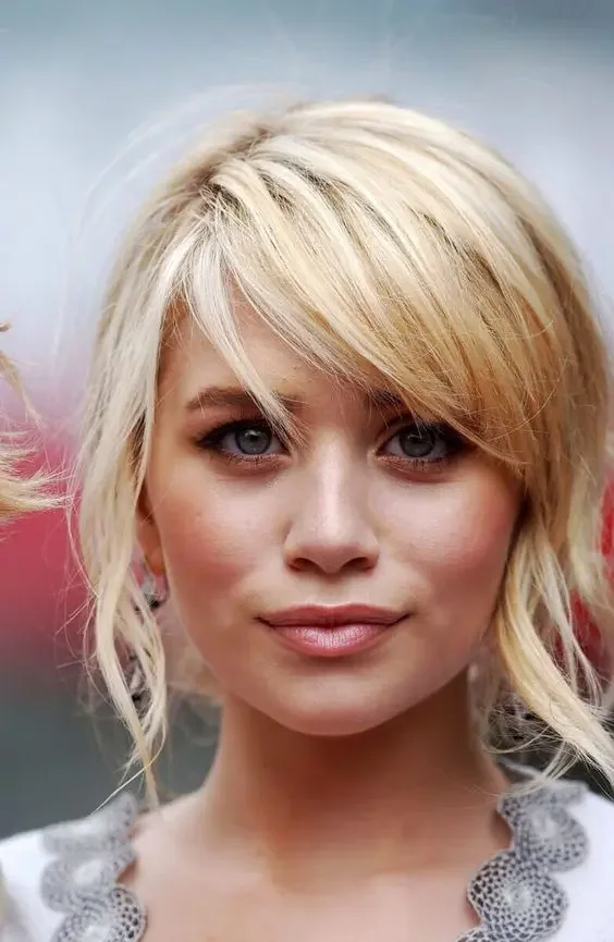 Blonde updo with messy locks down and side swept bangs for a cuter look.