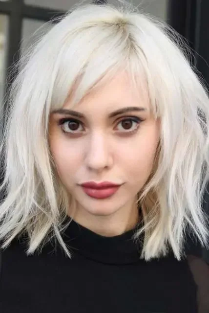 Medium-length shaggy icy blonde lob with side bangs.