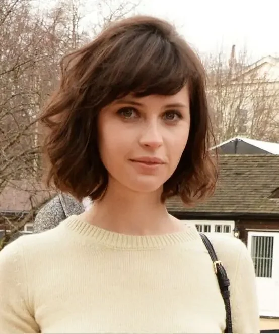Short dark brown bob with slight waves and side bangs.