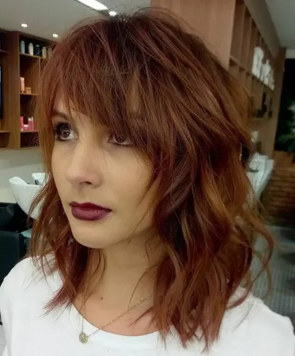 Tousled auburn low with messy side swept bangs.