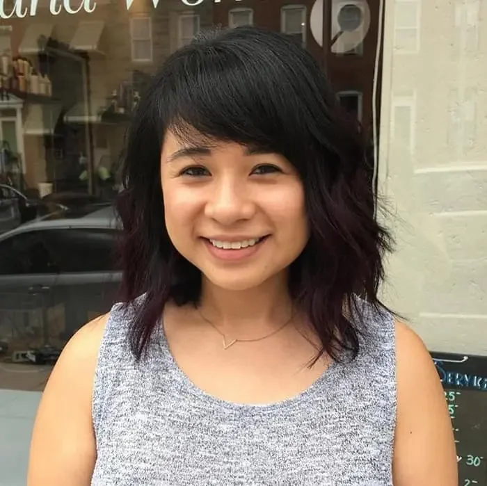 Black medium-length hair with deep purple tips and a shaggy haircut, with side bangs.