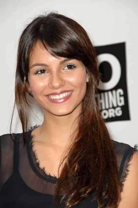 Long and shiny dark brown hair with locks down and side swept bangs in a low ponytail.