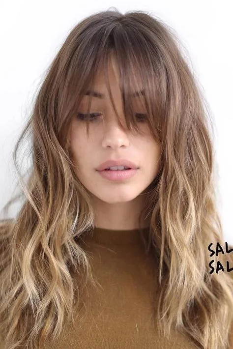 Light brown hair with an ombre effect to blonde, a layered haircut and wispy outgrown bangs for a feminine touch.