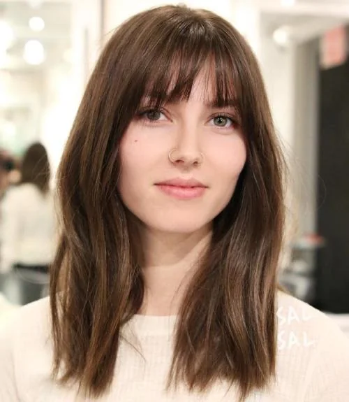 Medium-length brown hair with a a slightly parted thin and wispy fringe style.