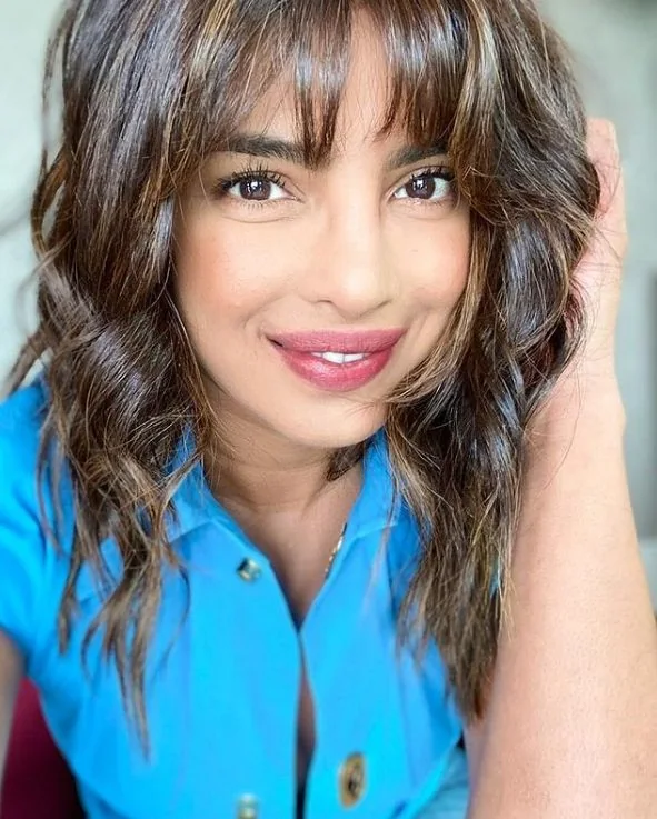 Priyanka Chopra Jonas's full, wispy bangs blend seamlessly into her layered mid length cut.