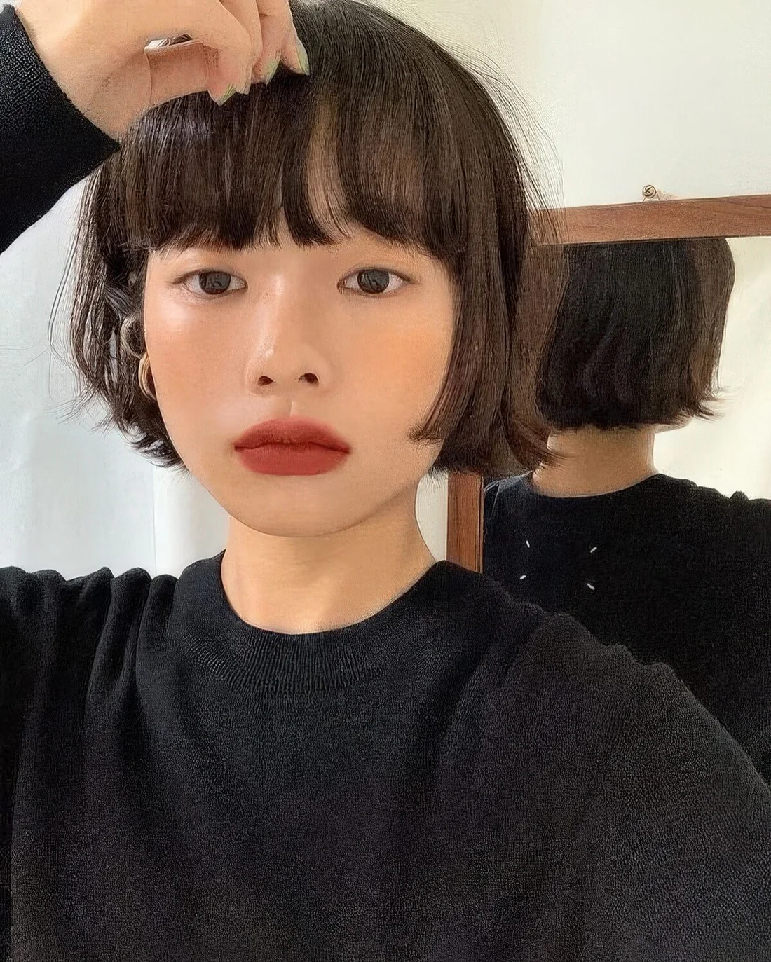 Brunette ear-length bob with outgrown bangs and messy texture.