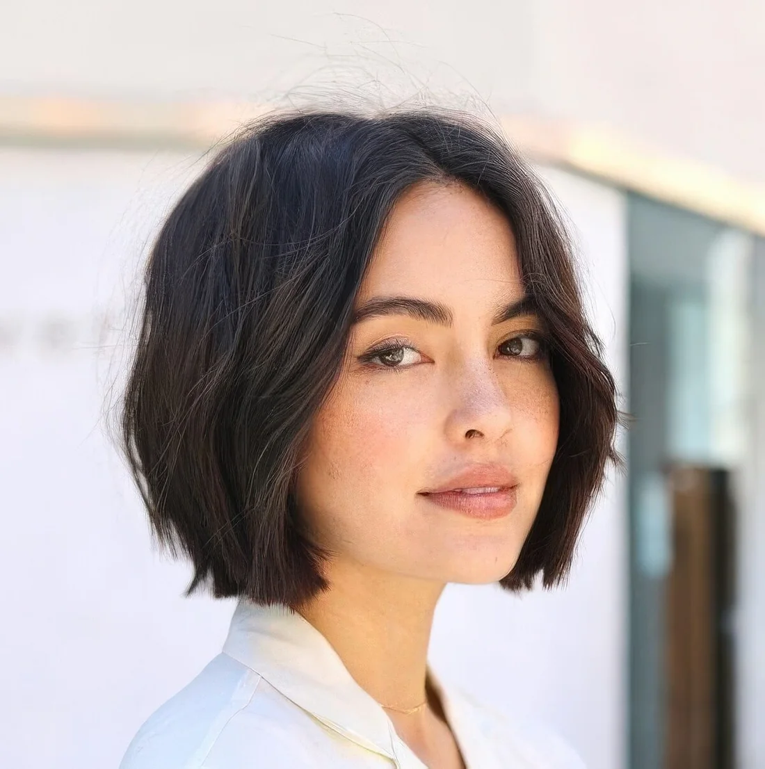 Relaxed brunette midi bob with middle part and slight waves.
