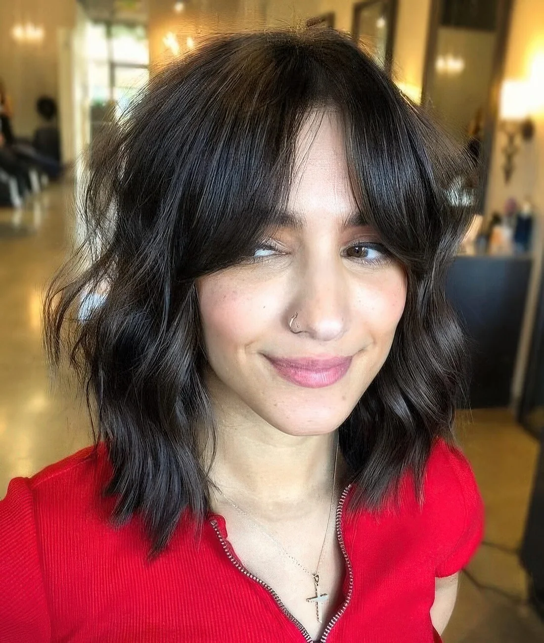 Dark brown shaggy long bob with messy waves and bottleneck bangs.