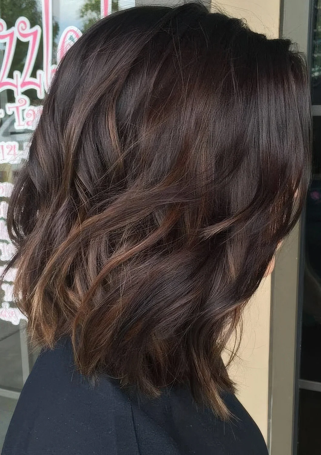 Dark brown wavy bob with caramel highlights.