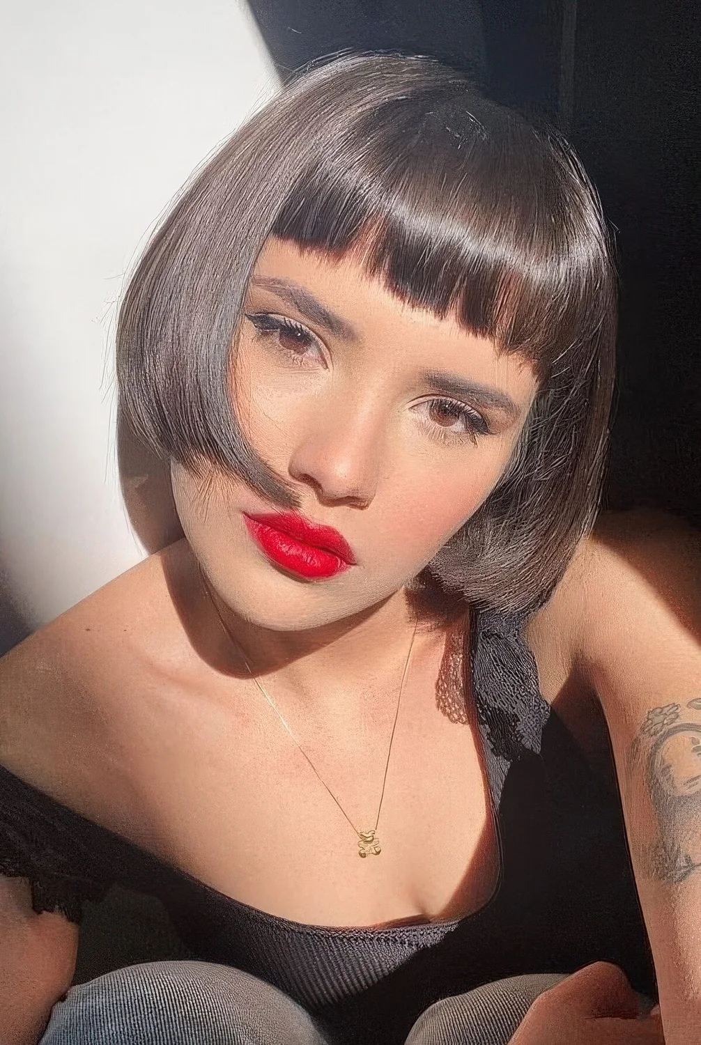 Dark brunette ear-length bob with baby bangs and curled ends plus a shiny finish.