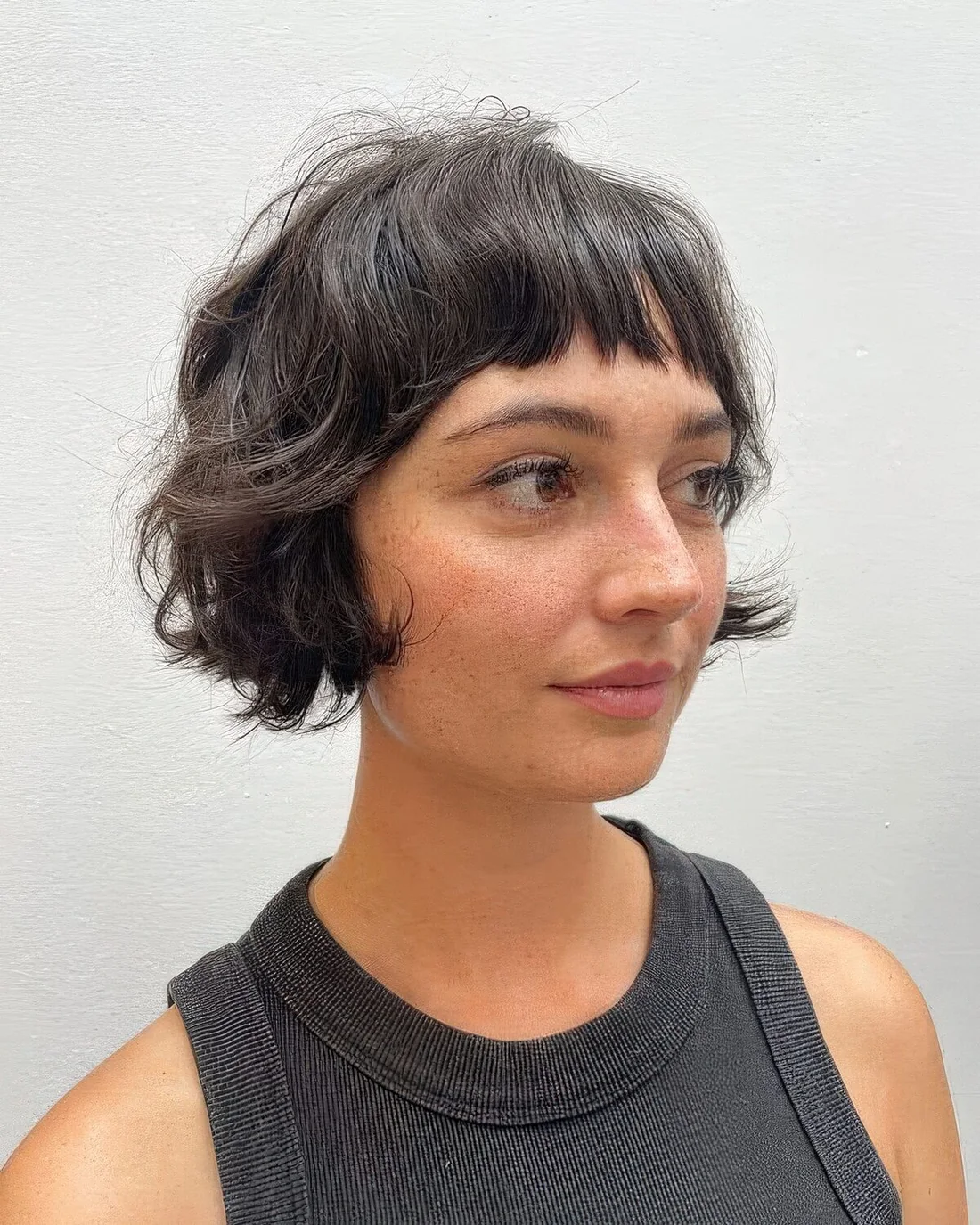 Black shaggy ear-length bob with wispy bangs.