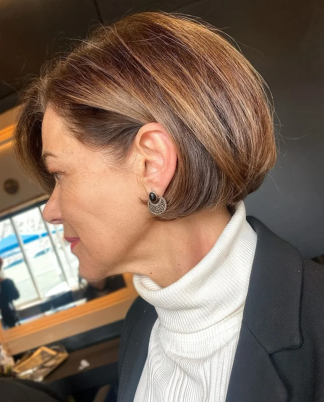 Brown ear-length bob with caramel balayage and side part.