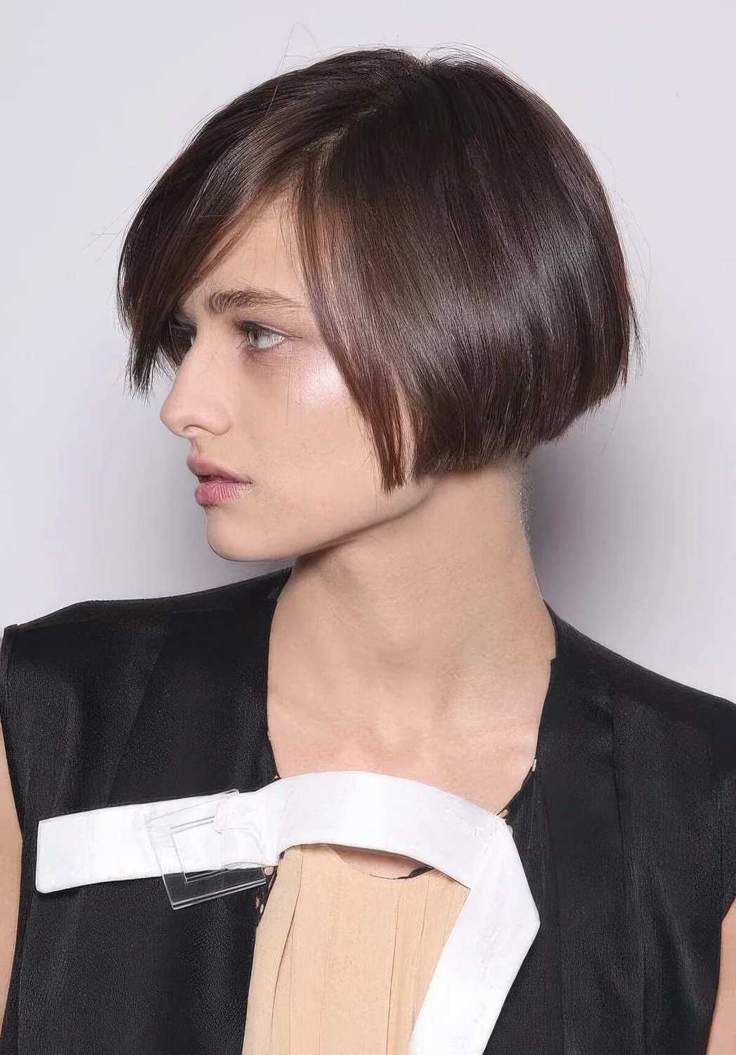 Brunette ear-length bob with side part, with a sleek finish.