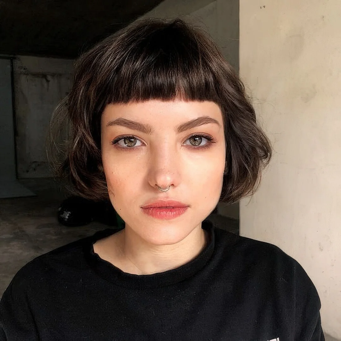 Dark brunette ear-length bob with baby bangs and waves.