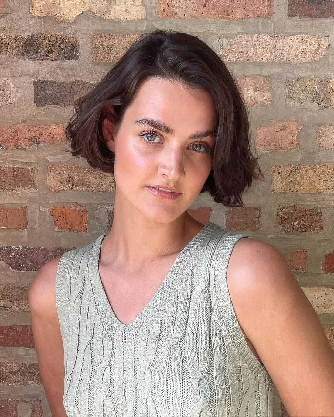Dark brunette ear-length hairstyle with a messy part and waves.