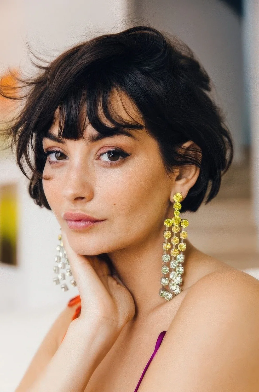 Black ear-length bob with wispy bangs and messy texture.