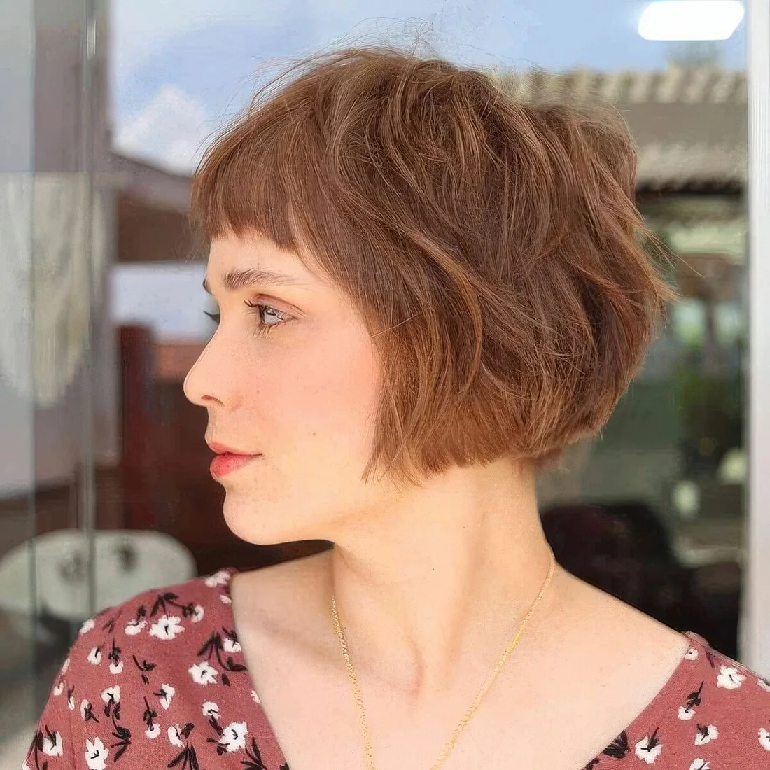 Shaggy ginger ear-length bob with mesys bangs and a lot of volume.