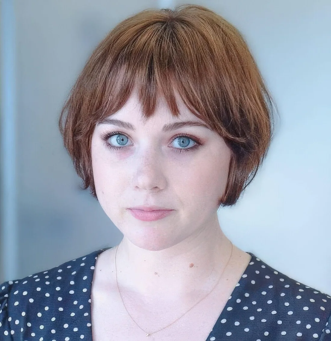 Short ginger brunette bob with wispy bangs.