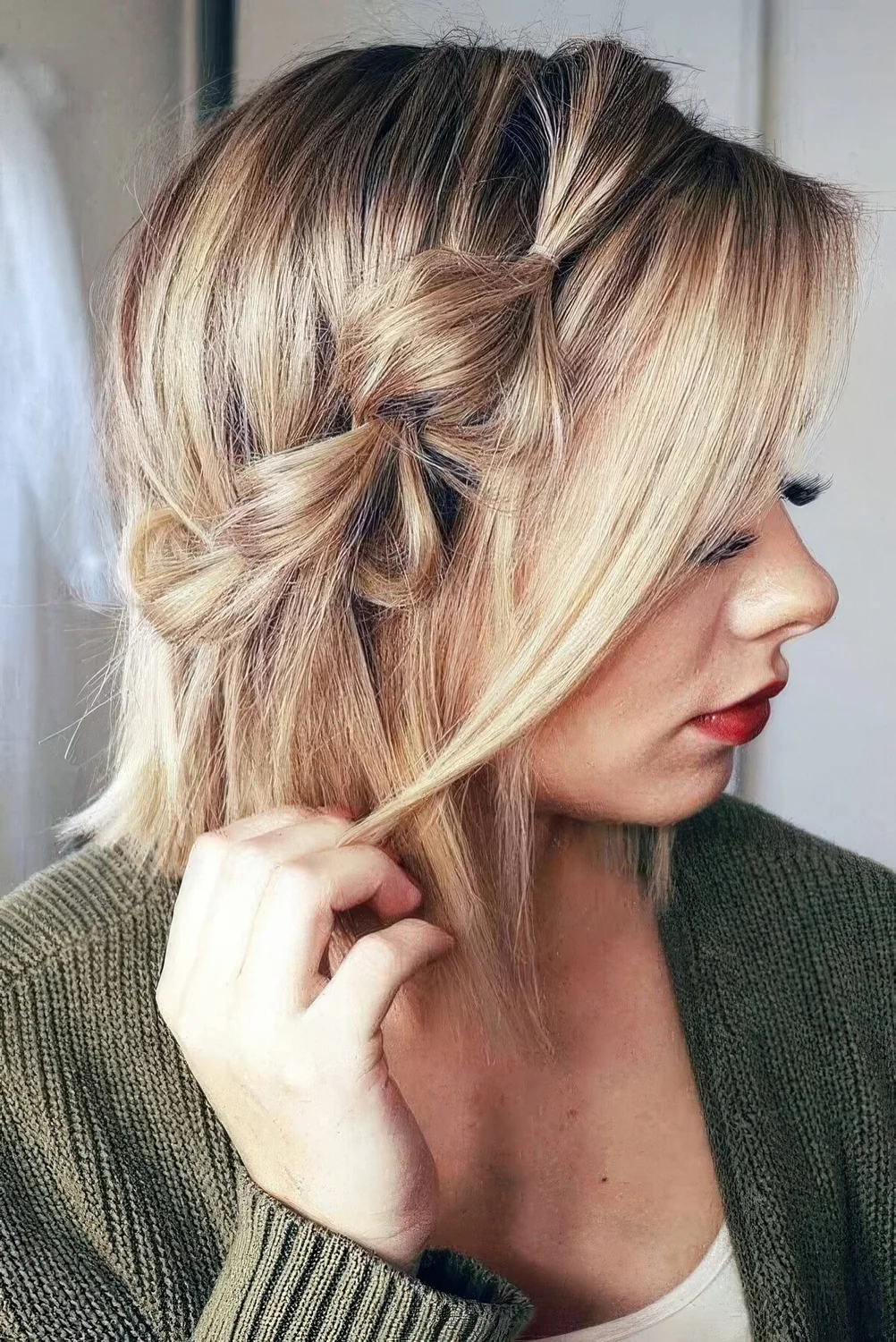 Blonde bob with a bubble side braid and some locks framing the face.