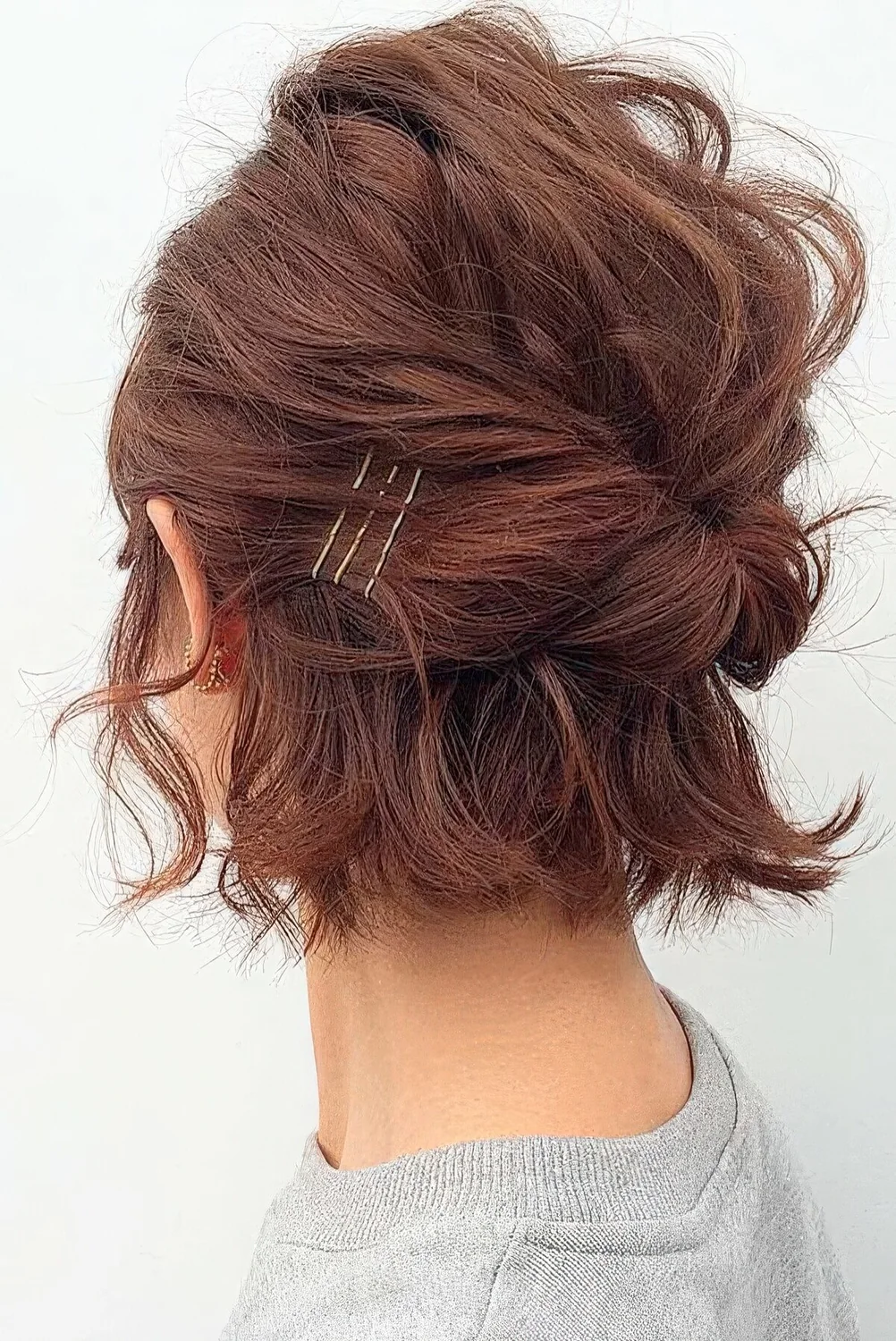 Emssy and textural burgundy midi bob styled with a bump on top and some twists plus bobby pins.
