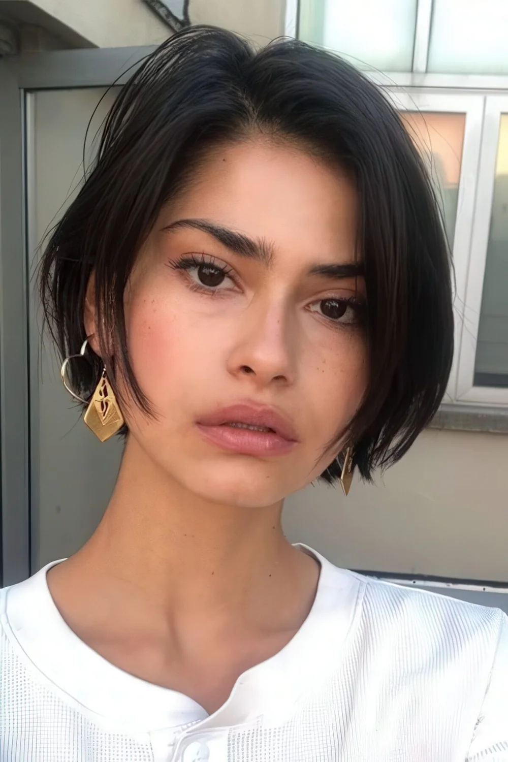 Rebellious French bob hairstyle in black, with side part and a bit of shaggy touches.