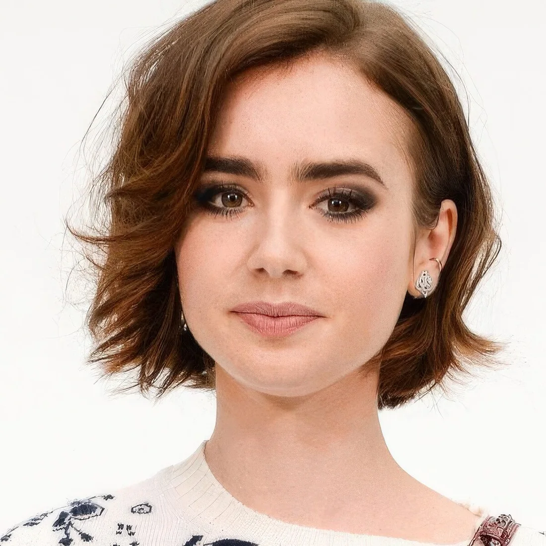 Short brunette bob with slight waves and side part, with a touch of ladder.