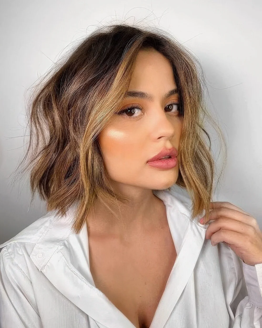Brown bob with blonde balayage and face-framing locks, with messy texture.