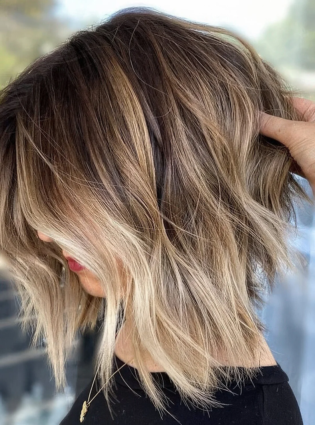 Brown bob wih blonde balayage, with messy waves and bangs.