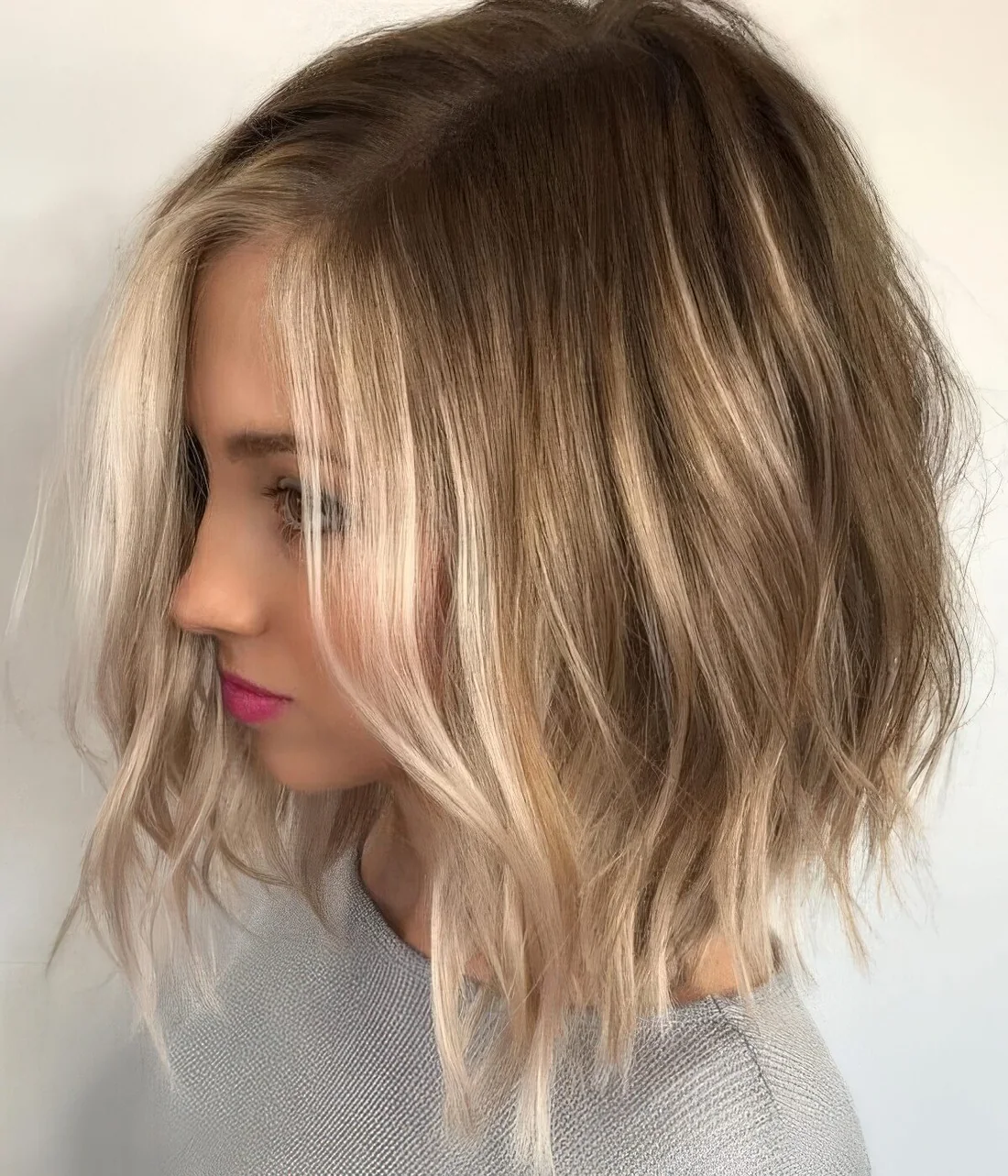 Light brown bob with blonde balayage and messy waves and texture.