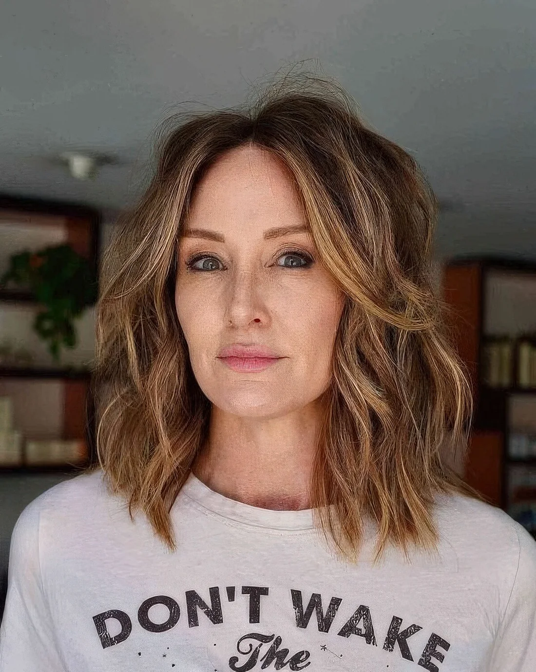 Wavy and shaggy outgrown bob in light brown and with honey highlights, with a lot of volume and center part.
