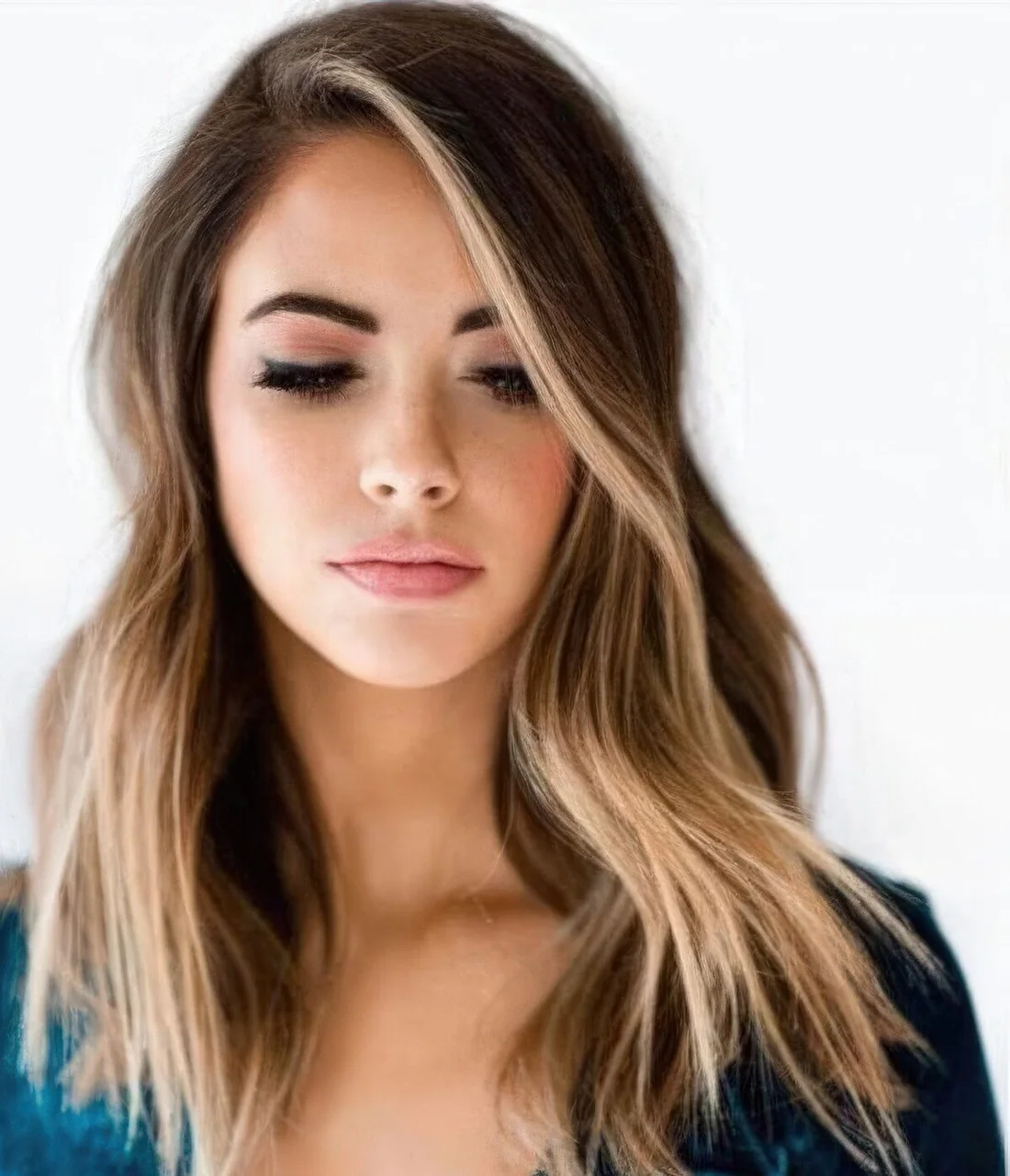 Brunette hair with face-framing sunkissed highlights and messy waves.