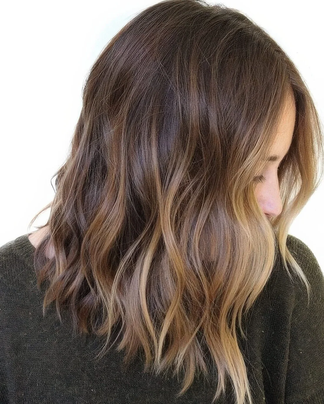 Rich brown wavy hair with chic sunkissed balayage and waves.