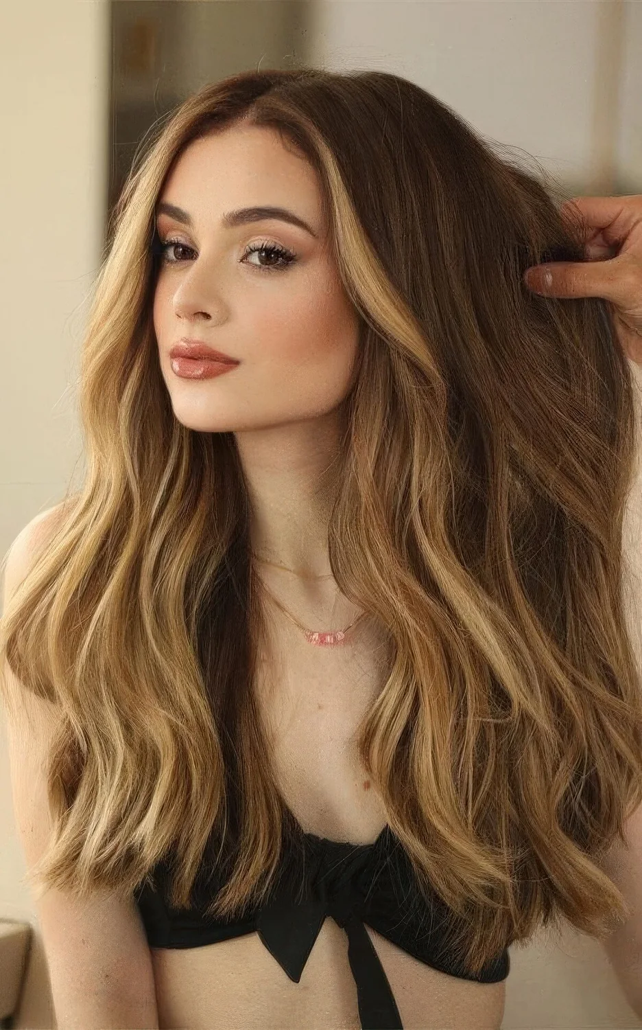 Long brunette hair with blonde face-framing highlights and balayage, volume and waves.
