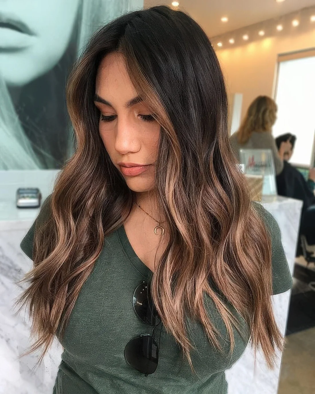 Long dark brunette hair with caramel face-framing highlights and balayage.
