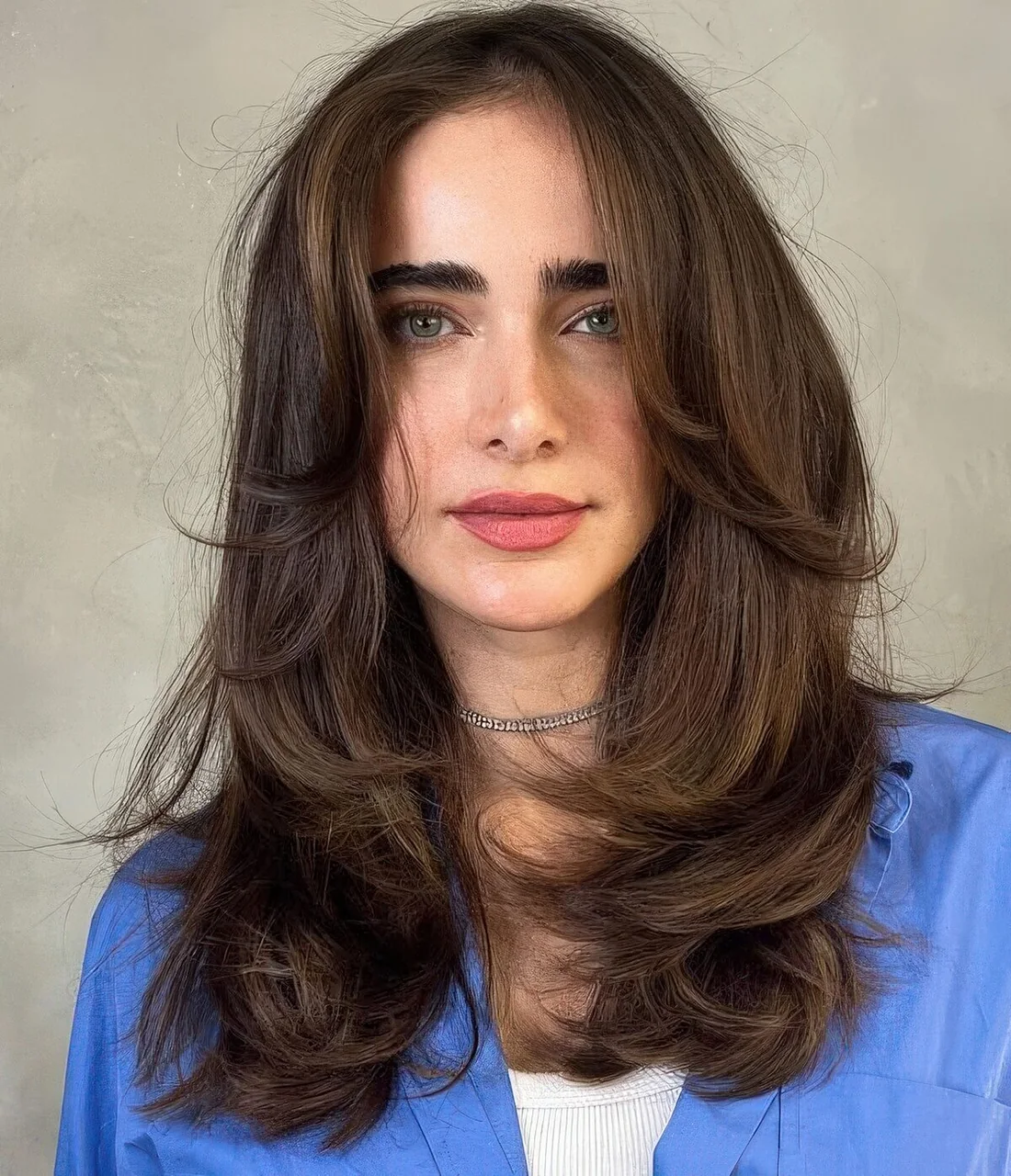 Dark brunette butterfly haircut with center part and lovely face-framing layers.