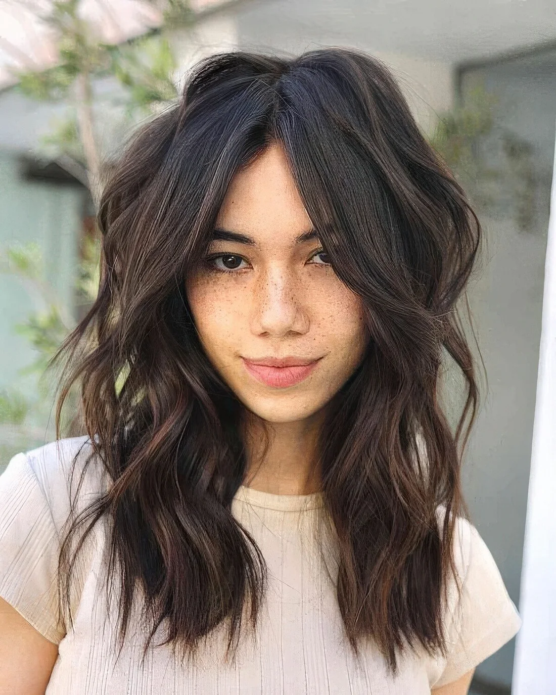 Dark brunette shaggy haircut with face-framing layers, center part, waves and a lot of dimension.