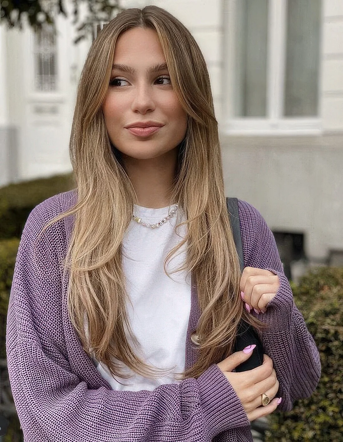 90s haircut with layers including face-framing ones, with center part and done in a soft light brunette shade.
