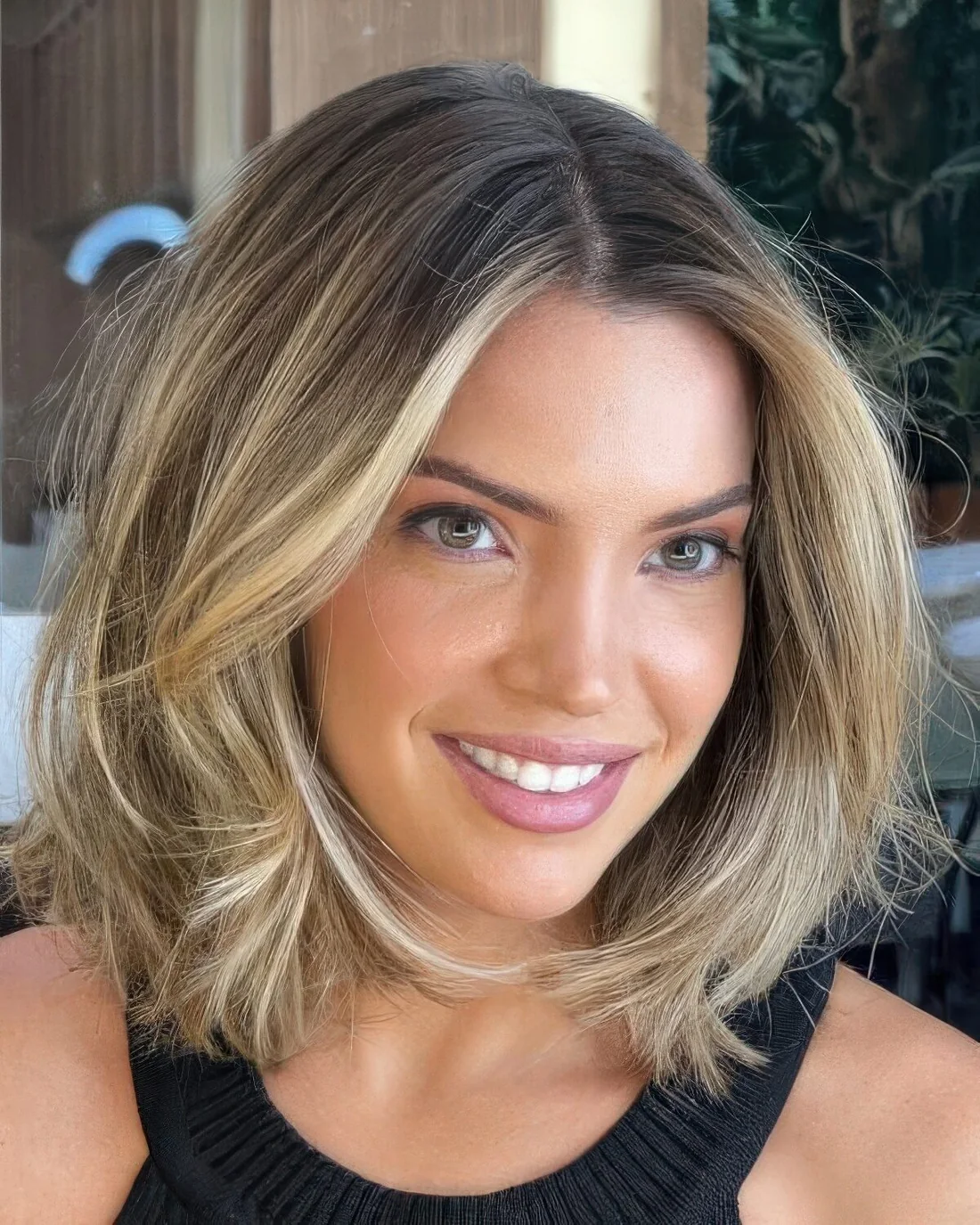 Medium-length low-maintenance hairstyle with blonde ombre and a darker root plus face-framing layers.