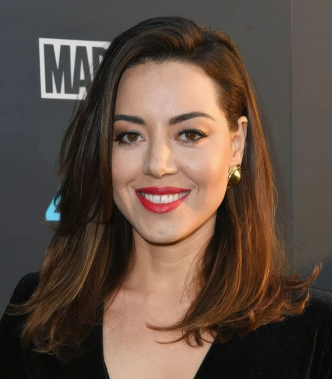 Aubrey Plaza wearing a medium layered haircut, with side part and face-framing layers.