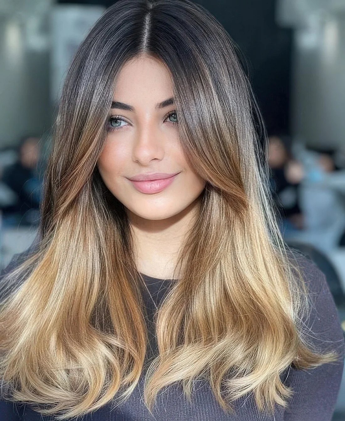 Light brown long hair with an ombre blonde effect and face-framing ombre layers plus middle part.