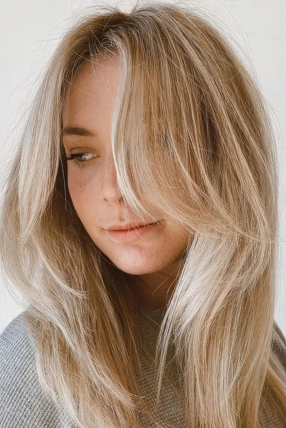 Long blonde hair with icy balayage and long layers framing the face.