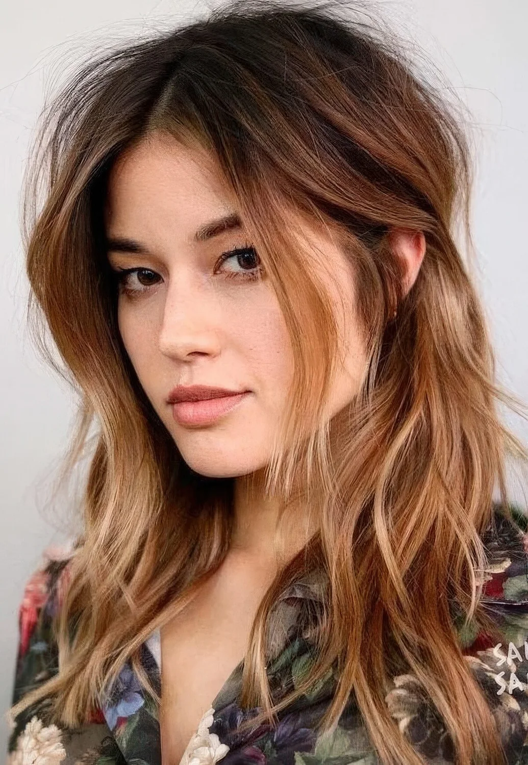 Dark brown root plus ombre caramel ends and messy waves plus layers around the face.