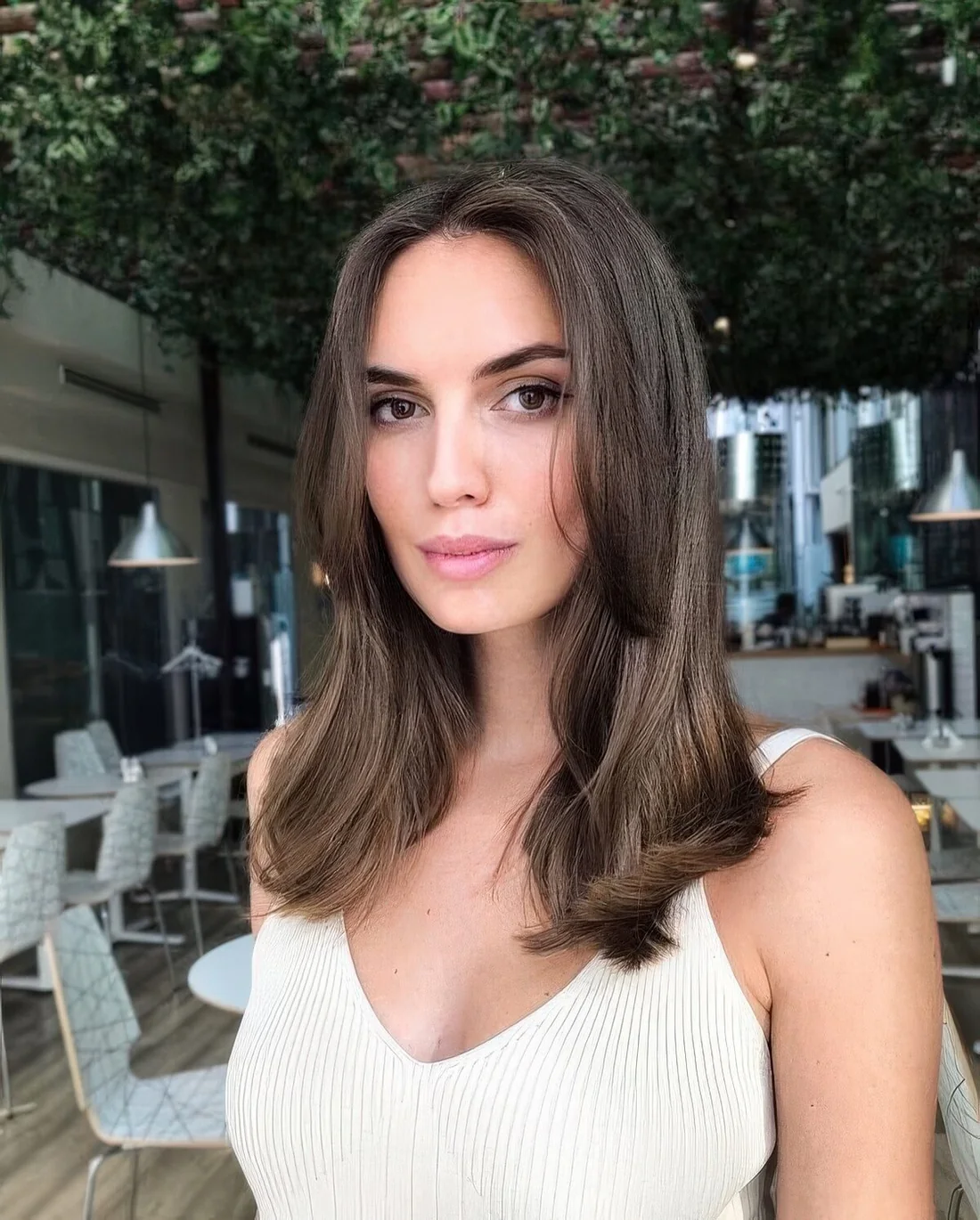 Dark brunette medium-length hair with face-framing layers and middle part.